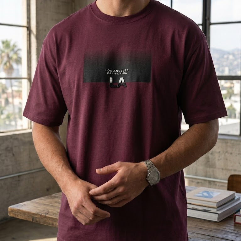 Man wearing a maroon t-shirt with a logo in an indoor setting